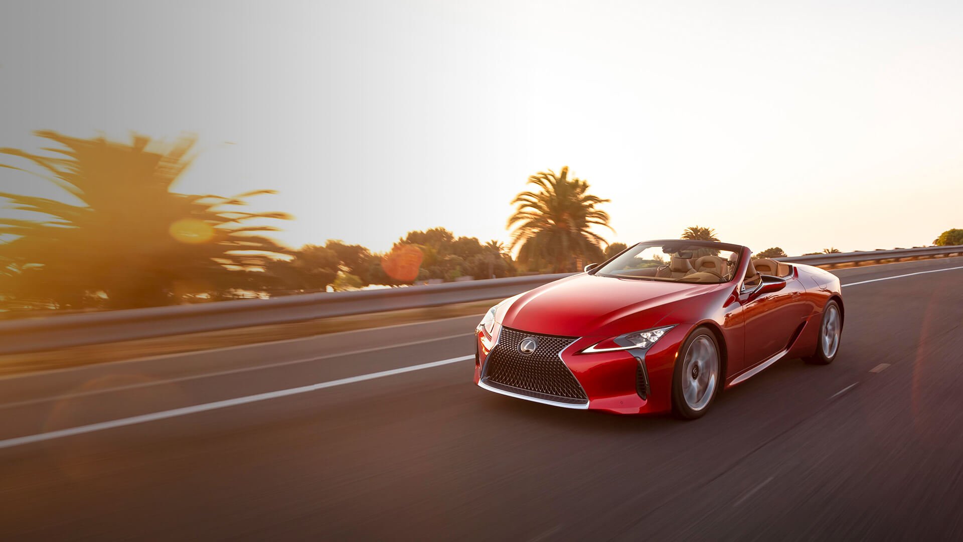Red Lexus LC Convertible being driven on the road with the top down.